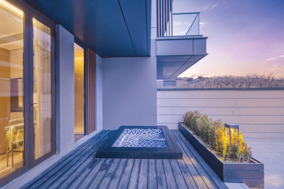 A modern outdoor pool area with a rectangular pool, wooden deck, and a planter with plants.
