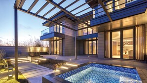 A modern outdoor pool area with a glass-enclosed patio, a hot tub, and a well-lit deck. - Crowne Plaza Zunhua Hot Spring Town by IHG (Tangshan)