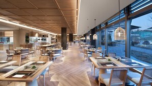 Un restaurant spacieux avec de hauts plafonds, un plancher en bois et de grandes fenêtres donnant sur l’extérieur.