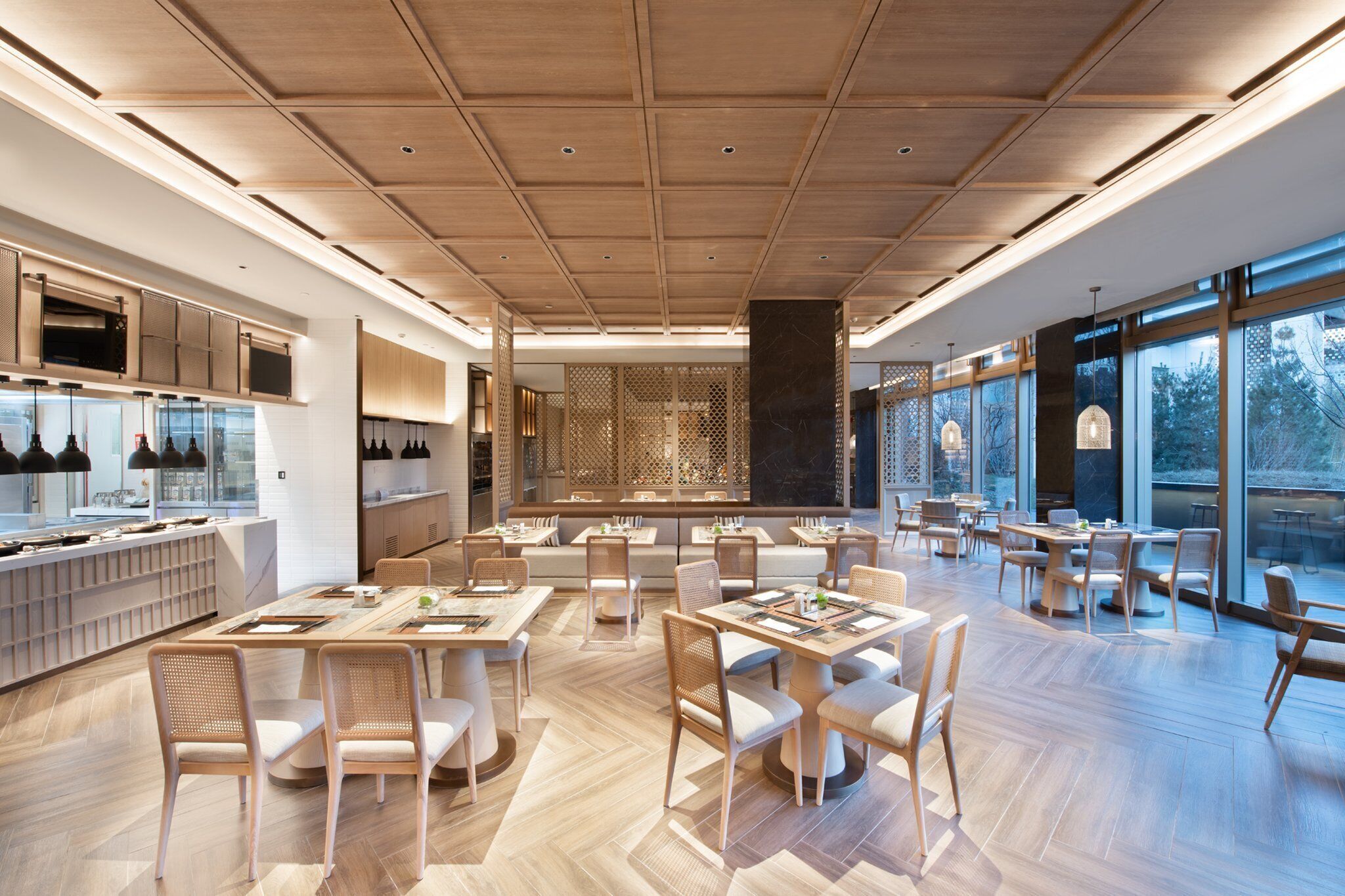 Un restaurant moderne doté d’un plancher en bois, de hauts plafonds et de grandes fenêtres.