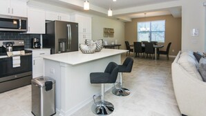 A modern kitchen with white cabinets, stainless steel appliances, and a central island with bar stools. - Premium Apartment 2BR/2BA • Near Disney • Storey Lake Resort [SL47316] (Kissimmee)