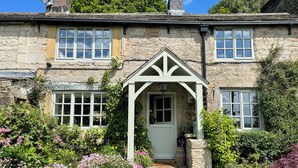 A stone house with a white porch, a small garden with flowers, and a brick chimney. - 3 bedroom accommodation in Midgehole, Hebden Bridge (Midgehole, Hebden Bridge)