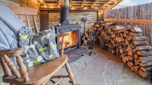 A cozy wooden cabin with a fireplace, a stack of firewood, and a rocking chair. - 3 bedroom accommodation in Midgehole, Hebden Bridge (Midgehole, Hebden Bridge)