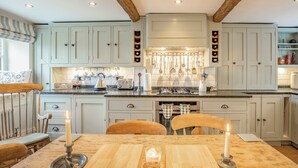 A kitchen with light blue cabinets, a wooden dining table with candles, and a hanging utensil rack. - 3 bedroom accommodation in Midgehole, Hebden Bridge (Midgehole, Hebden Bridge)
