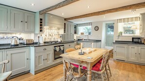 A kitchen with wooden beams, a dining table with chairs, and a view of the outdoors. - 3 bedroom accommodation in Midgehole, Hebden Bridge (Midgehole, Hebden Bridge)