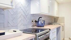 Une cuisine moderne avec un dosseret de carreaux disposés en motif chevron, une cuisinière en acier inoxydable et un four encastré.