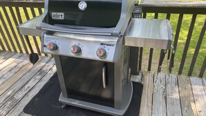Ein tragbarer Weber Spirit Grill mit digitalem Thermometer auf einer Holzterrasse.