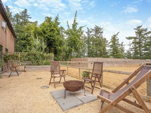 An outdoor seating area with wooden chairs and a grill, surrounded by a wooden fence and trees. - Ground Floor: 
Open plan living space. (Midgham)