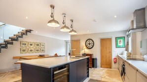 Une cuisine moderne dotée d’un îlot central, de luminaires suspendus et d’un escalier menant à un niveau supérieur.