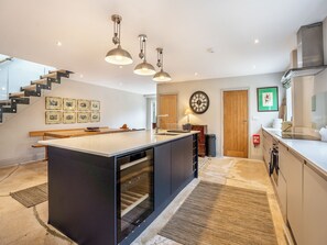 A modern kitchen with a central island, pendant lighting, and a staircase leading to an upper level. - Ground Floor: 
Open plan living space. (Midgham)