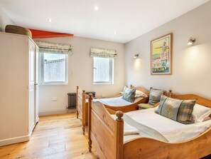 A bedroom with two wooden beds, a radiator, and two windows with curtains. - Ground Floor: 
Open plan living space. (Midgham)