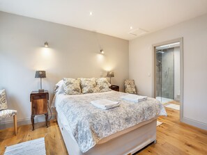 A bedroom with a large bed, two bedside tables with lamps, a chair, and a glass shower enclosure. - Ground Floor: 
Open plan living space. (Midgham)