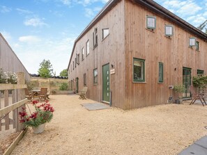 Un edificio in legno con diverse finestre e una porta, circondato da ghiaia e piante in vaso.