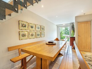 A spacious dining area with a long wooden table, surrounded by chairs, and a staircase leading to an upper level. - Ground Floor: 
Open plan living space. (Midgham)