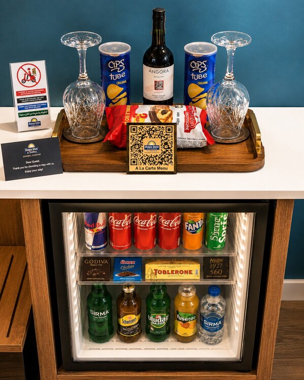 Minibar com diversos petiscos, bebidas e uma garrafa de vinho Angora.