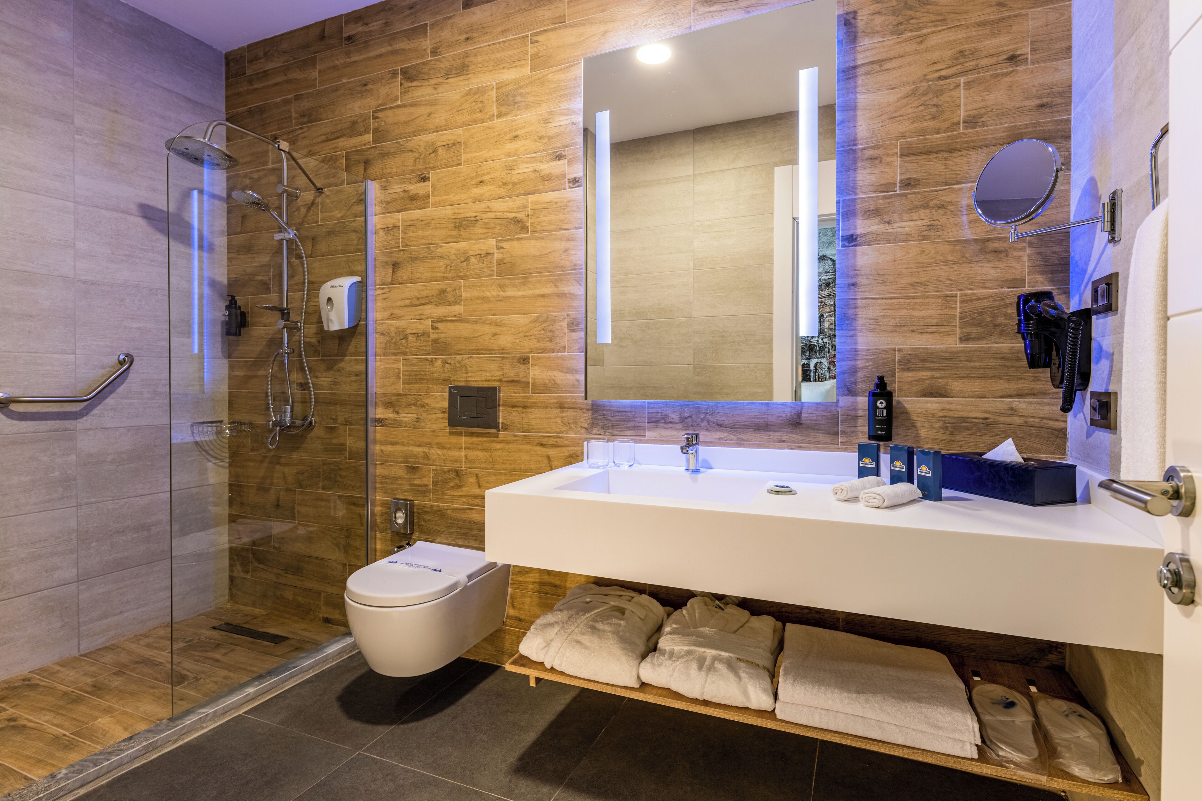 Un baño moderno con cabina de ducha de vidrio, un lavabo blanco y un espejo.