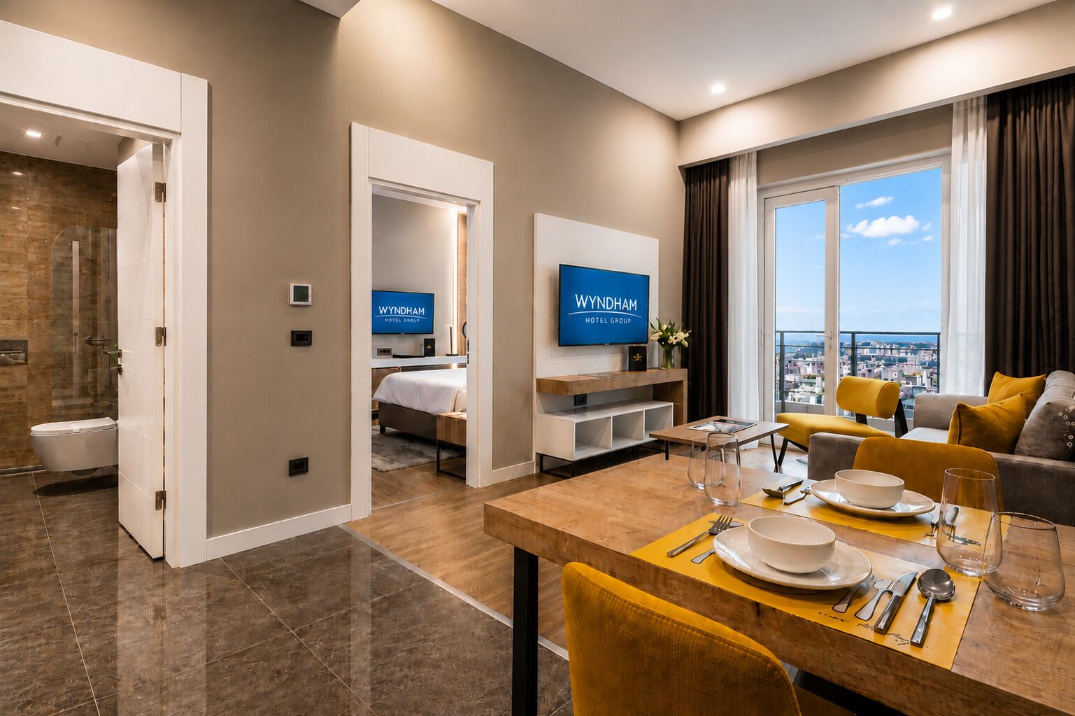 A modern hotel room with a dining area, a TV, and a city view.