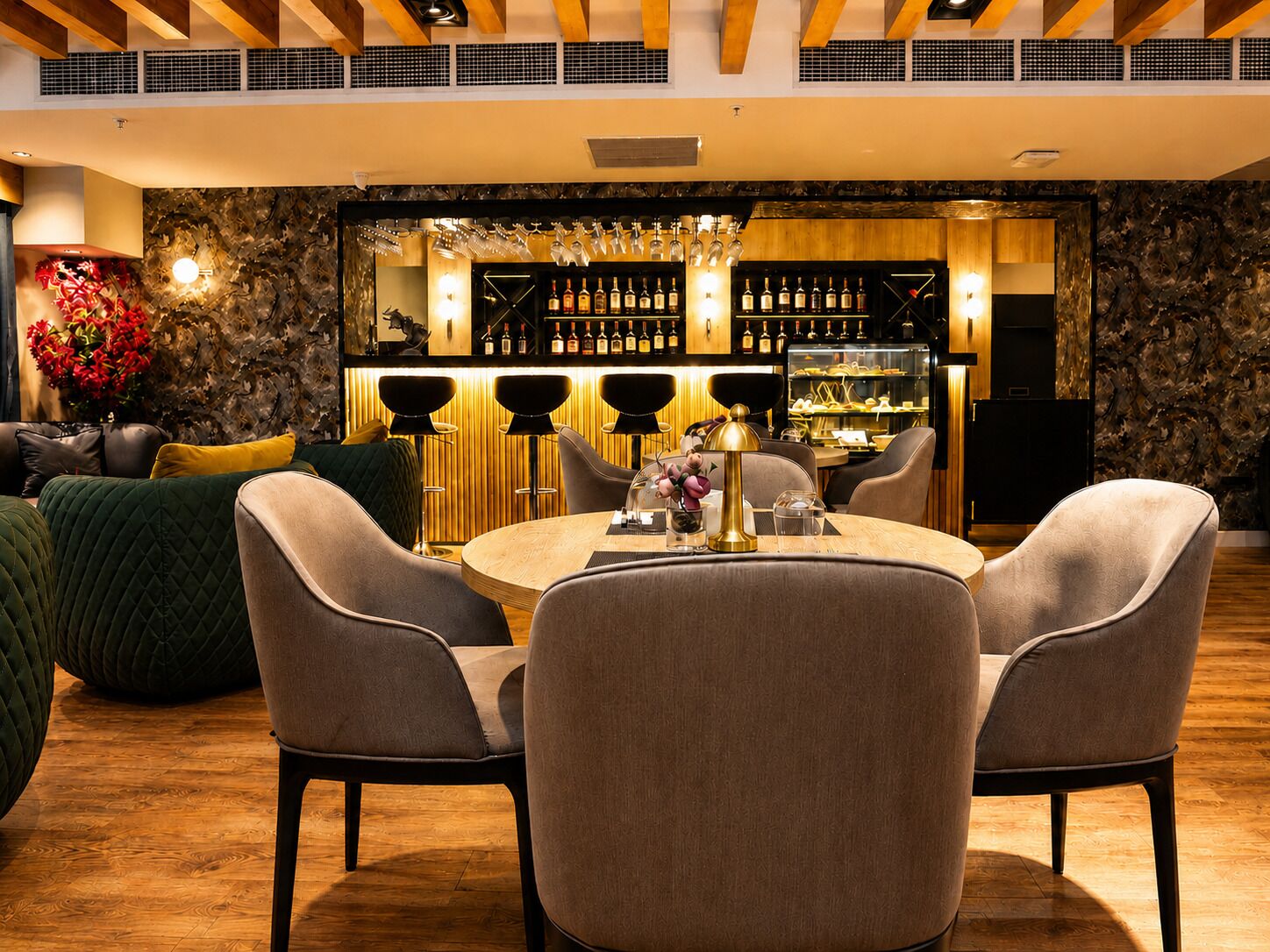A modern bar area with a round table, bar stools, and a wine display.