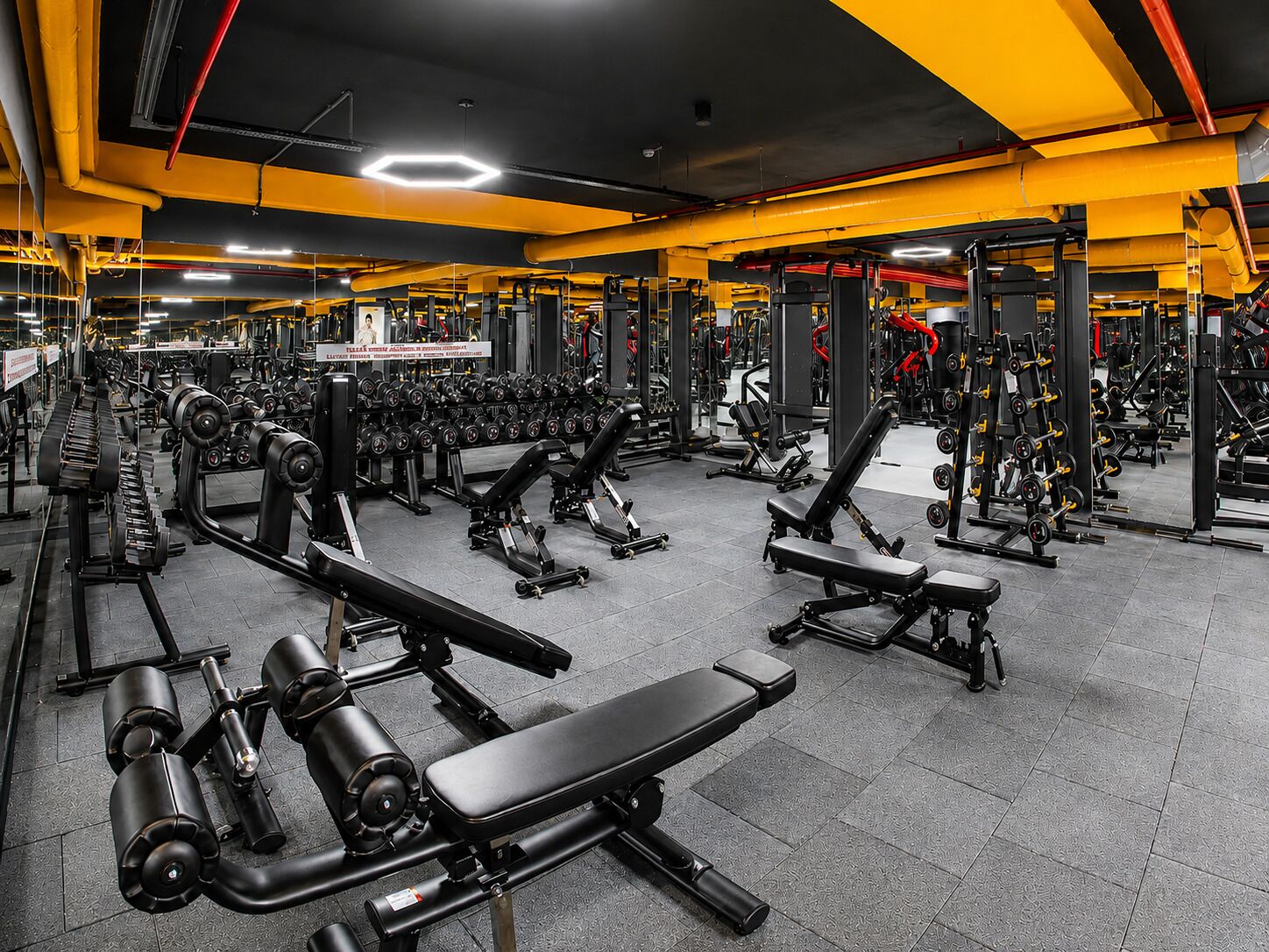 A gym with various exercise equipment, benches, and weight machines.