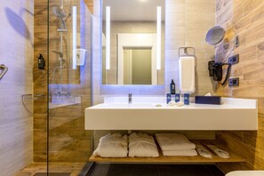 Uma casa de banho moderna com cabine de duche em vidro, uma sanita branca, um porta-toalhas e um espelho.