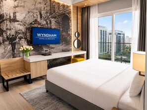Quarto de hotel moderno com cama, escrivaninha, televisão e vista para a cidade.
