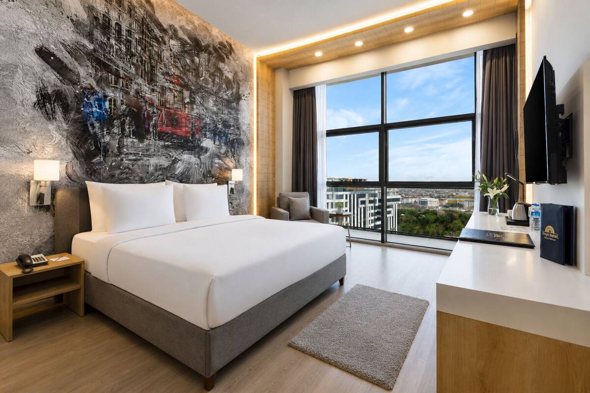 Une chambre d’hôtel moderne dotée d’un grand lit, d’un bureau, d’une télévision à écran plat et offrant une vue sur la ville.