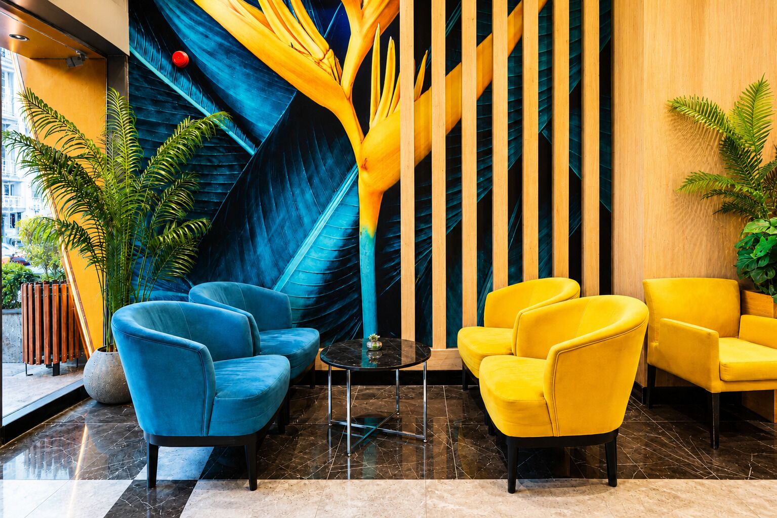 A lobby with blue and yellow chairs, a black table, and a large wall mural.