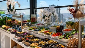Un bufé con diversas opciones de comida y vistas a la ciudad a través de amplias ventanas.