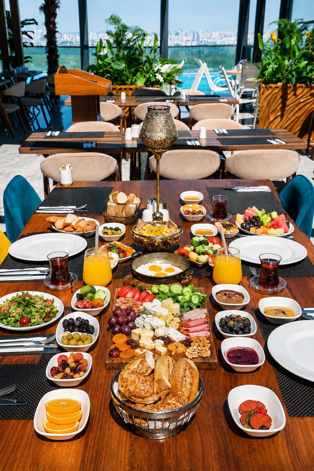 A table set for breakfast with various dishes, a lamp, and a view of the city.