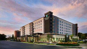 Un hôtel moderne, reconnaissable à son grand panneau « Embassy Suites », qui s’étend sur plusieurs étages et dispose d’un parking.