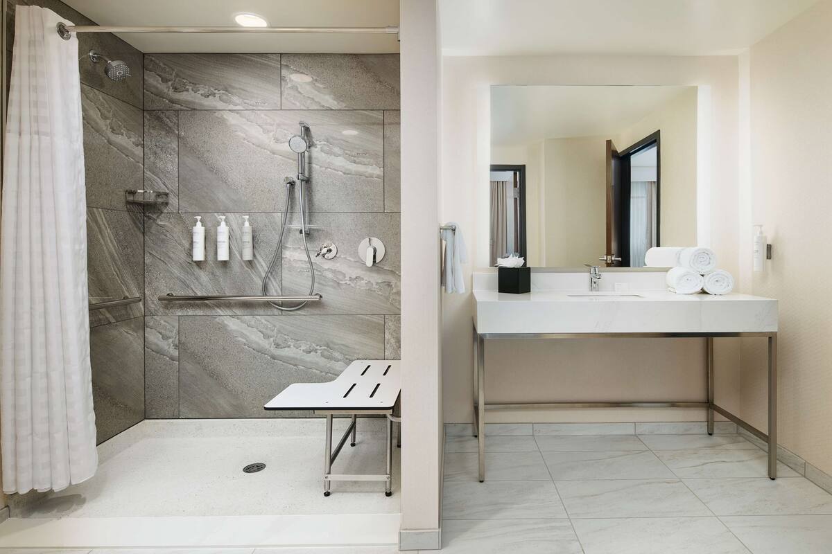 Een moderne badkamer met een douche, wastafel en spiegel.