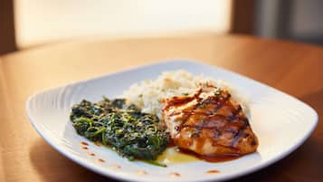 A plate with grilled chicken, rice, and spinach on a white plate.