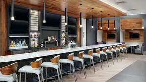 Un bar moderne doté d’un long comptoir, de plusieurs téléviseurs et d’un large choix de bouteilles.