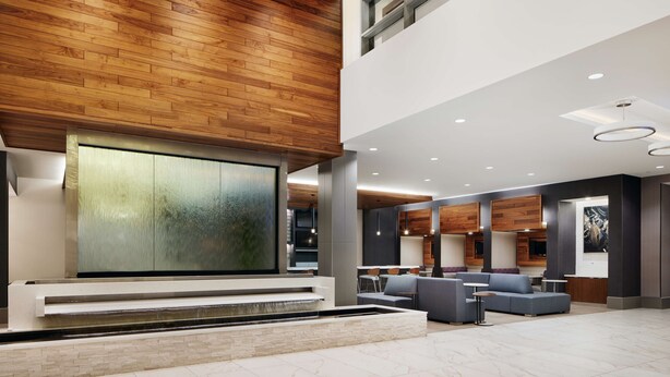 Un hall d’entrée spacieux, doté d’un grand écran fixé au mur, d’un espace salon et d’un plafond en bois.