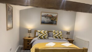 A bedroom with a wooden bed, two bedside tables with lamps, a painting on the wall, and a plaid floor. - Newly converted barn with hot tub,stylish interior and outdoor space (Roundthwaite)