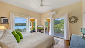 Un dormitorio con una cama grande, televisión y balcón con vista al mar.