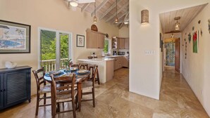Una cocina amplia con armarios de madera, un comedor con una mesa redonda y sillas, y vistas a través de un ventanal.