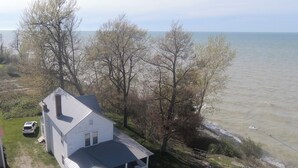 A white house with a porch, located near a body of water.