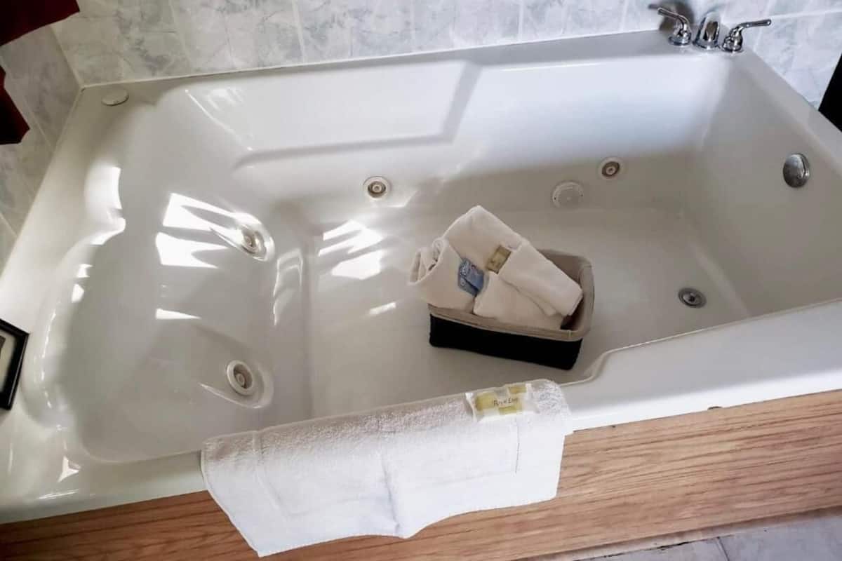 A bathroom with a white bathtub, a towel, and a small box.