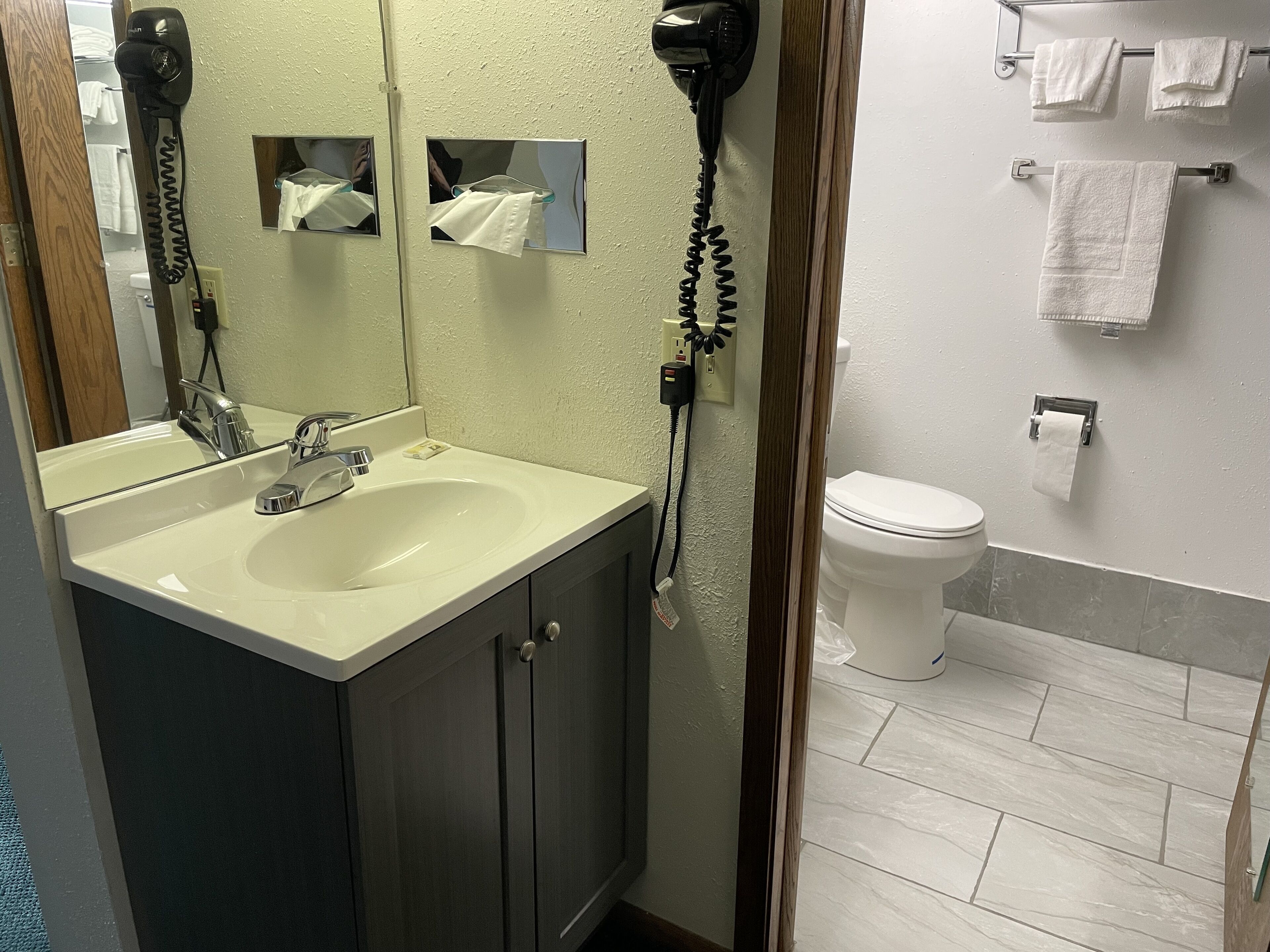 Un baño con lavamanos, espejo, secador de pelo y retrete.