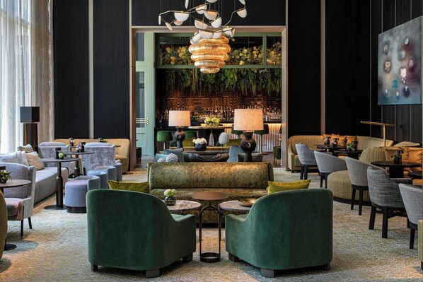 A modern lounge area with sofas, armchairs, and a bar counter.
