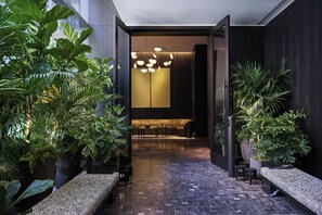 A modern indoor space with a dark-toned reception area, a patterned floor, and various potted plants.