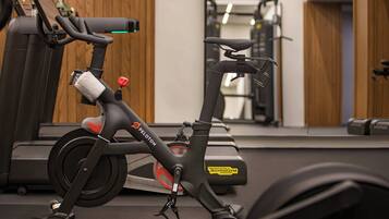 Un vélo d’appartement doté d’un panneau de commande et d’un miroir, installé dans une salle de sport.