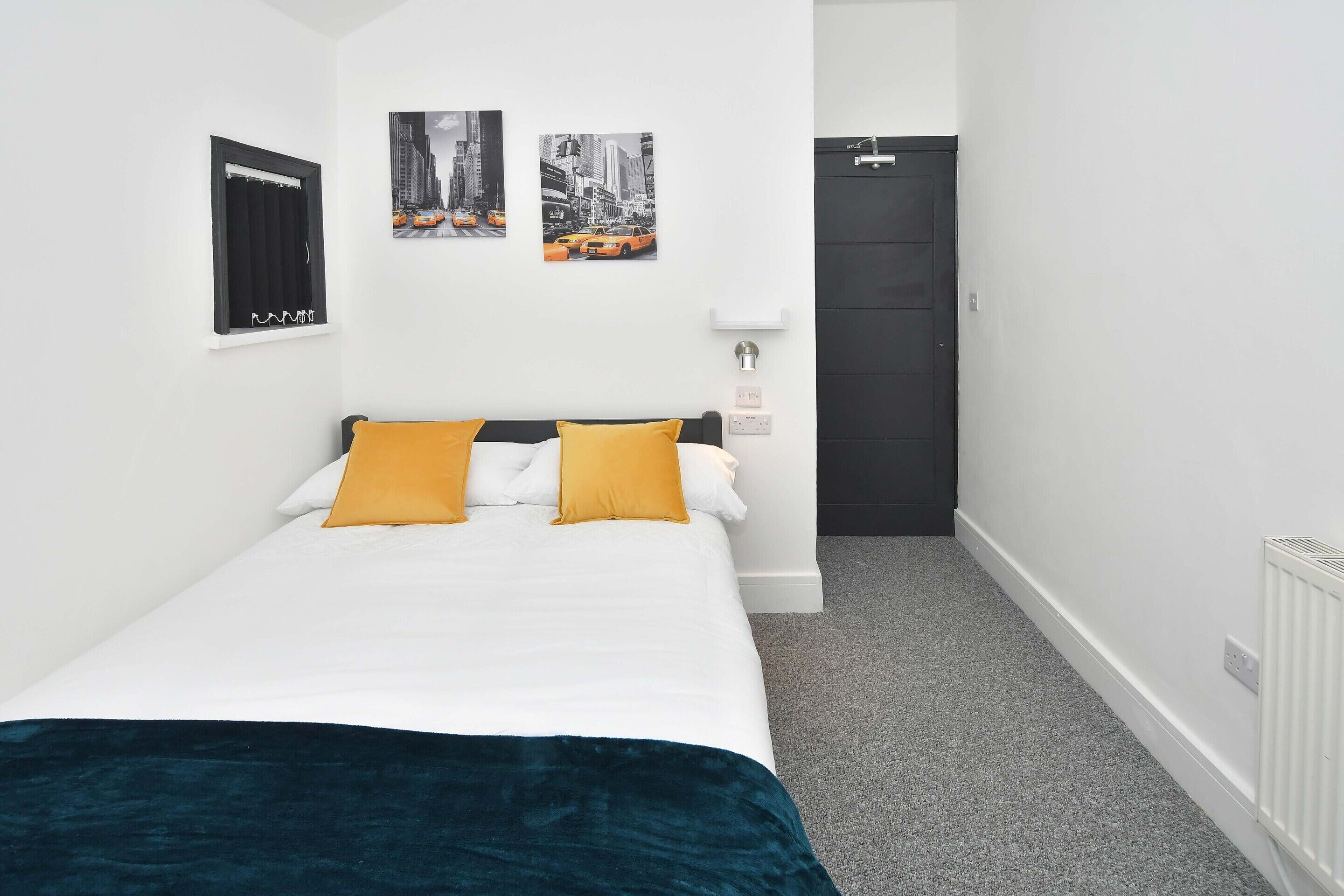 Une chambre à coucher bien rangée, avec un lit, deux oreillers, une table de chevet, une lampe et une porte.