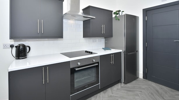 A modern kitchen with dark cabinets, a white countertop, an oven, and a refrigerator. - Townhouse @ 202 Walthall Street Crewe (Crewe)