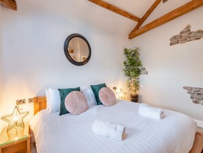 A neatly made bed with pillows, a bedside lamp, and a star-shaped light on a wooden nightstand.