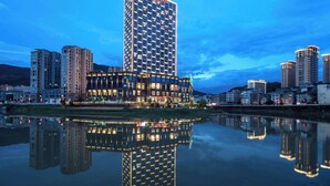 Un hotel de gran altura con diseño arquitectónico moderno, que destaca por una imponente torre central y varios edificios circundantes.