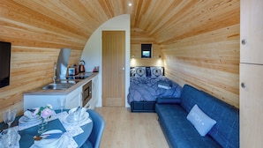 Una habitación compacta, con piso de madera, una kitchenette, una zona de comedor y un sofá.