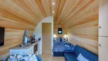 Une pièce compacte, dotée d’un plancher en bois, d’un coin cuisine, d’un espace repas et d’un canapé.
