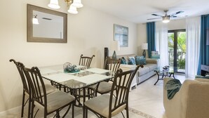 Un comedor con una mesa de vidrio, sillas de madera y un candelabro. En la sala de estar, hay un sofá y una mesa de centro.